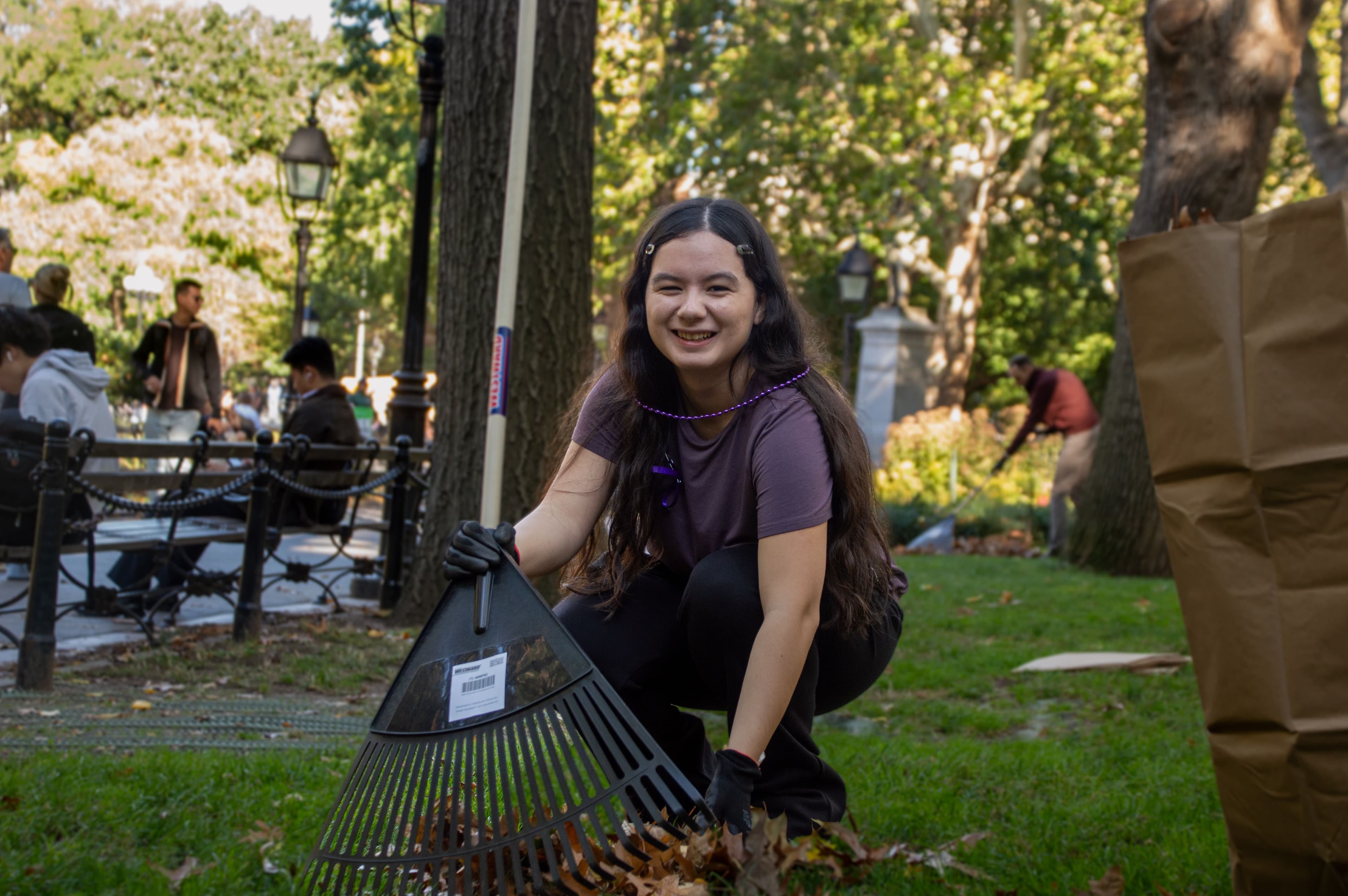 A person holds a rake in Washington Square Park.