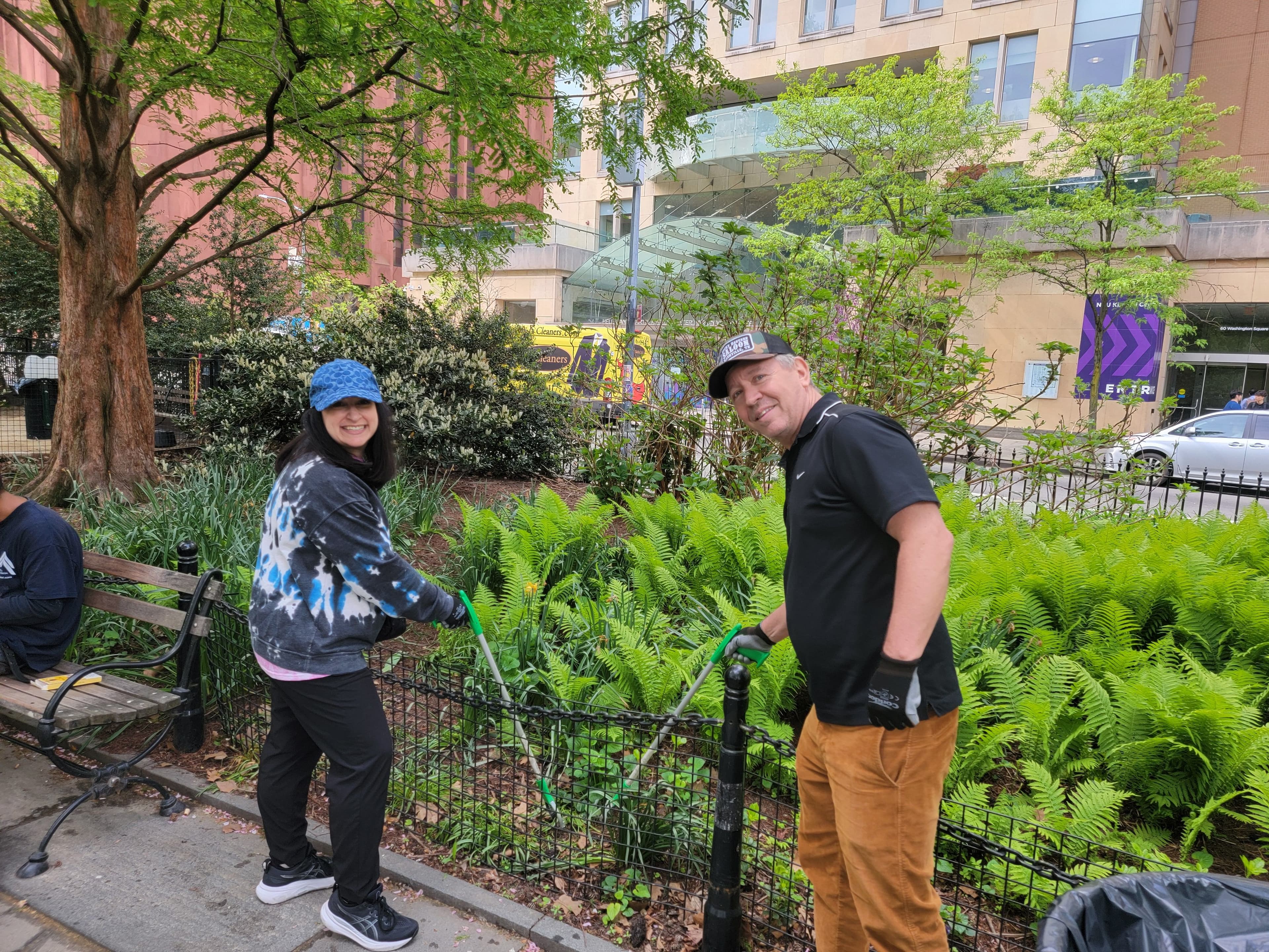 Two people hold trash grabbers in Washington Square Park.