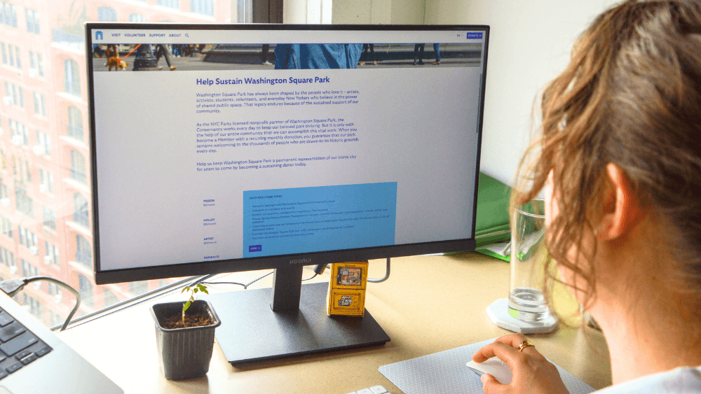 A person uses a computer with the Washington Square Park Conservancy's website pulled up on the screen.