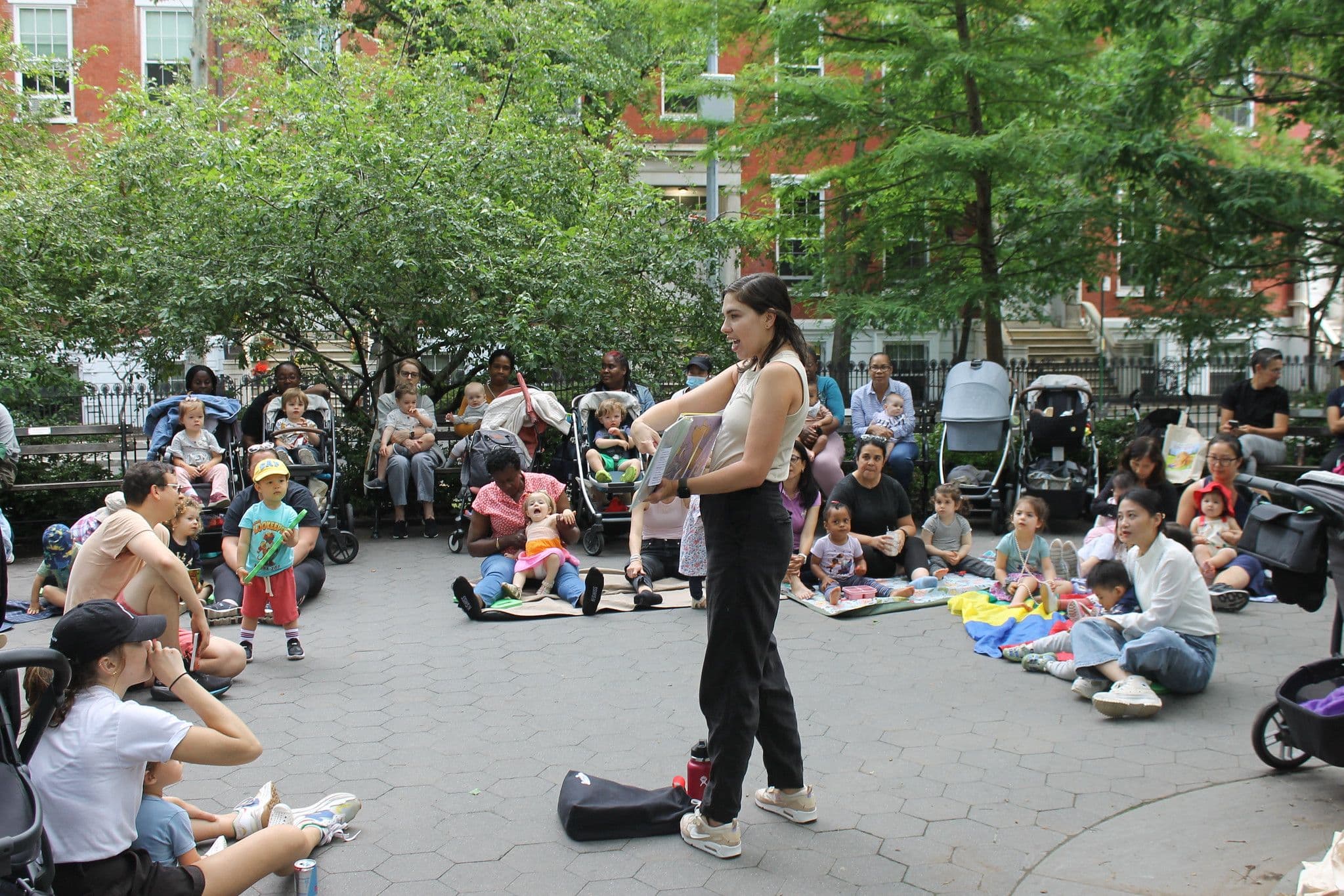 A person reads a story to a group of kids and families.