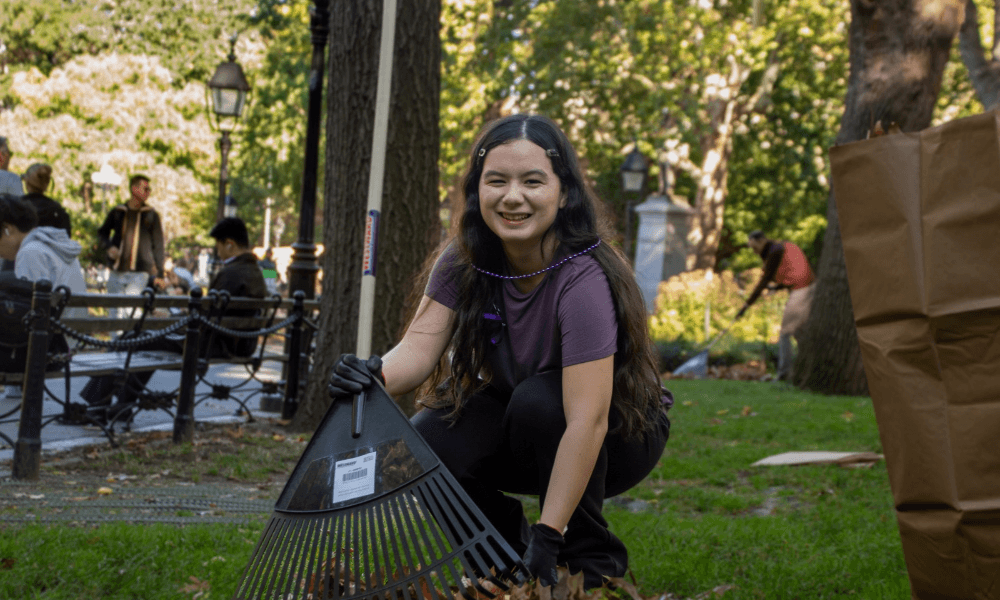 A person holds a rake in Washington Square Park.