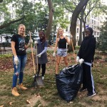 four volunteers pose with cleaning tools and smile at the camera