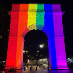 the arch at night is illuminated with rainbow lights
