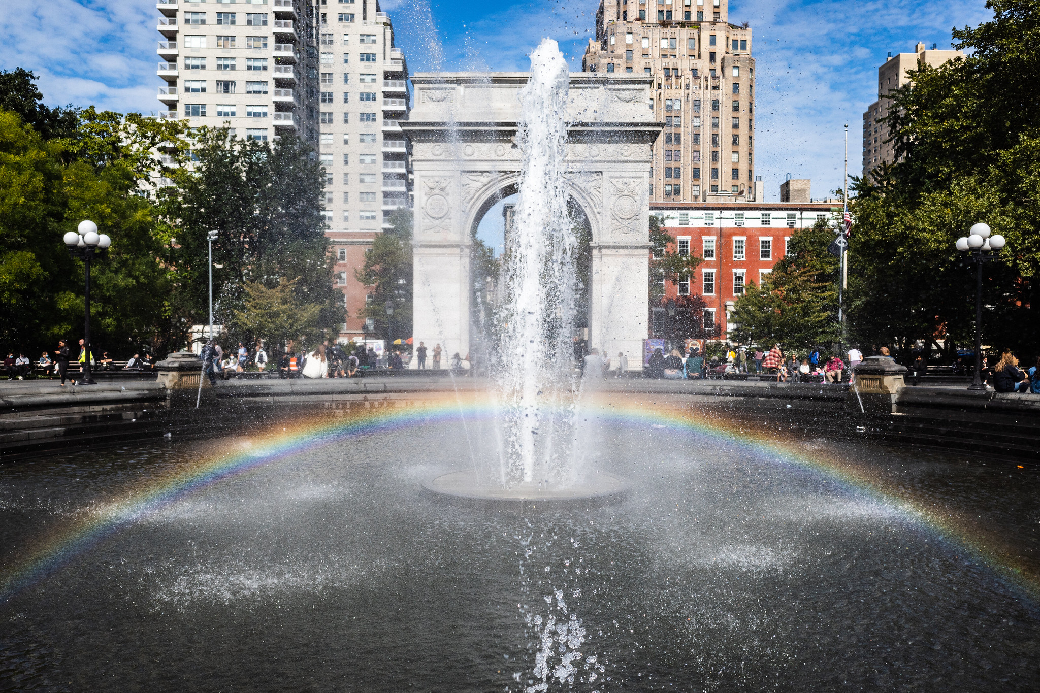 a rainbow appears in the fountain with the arch in the background