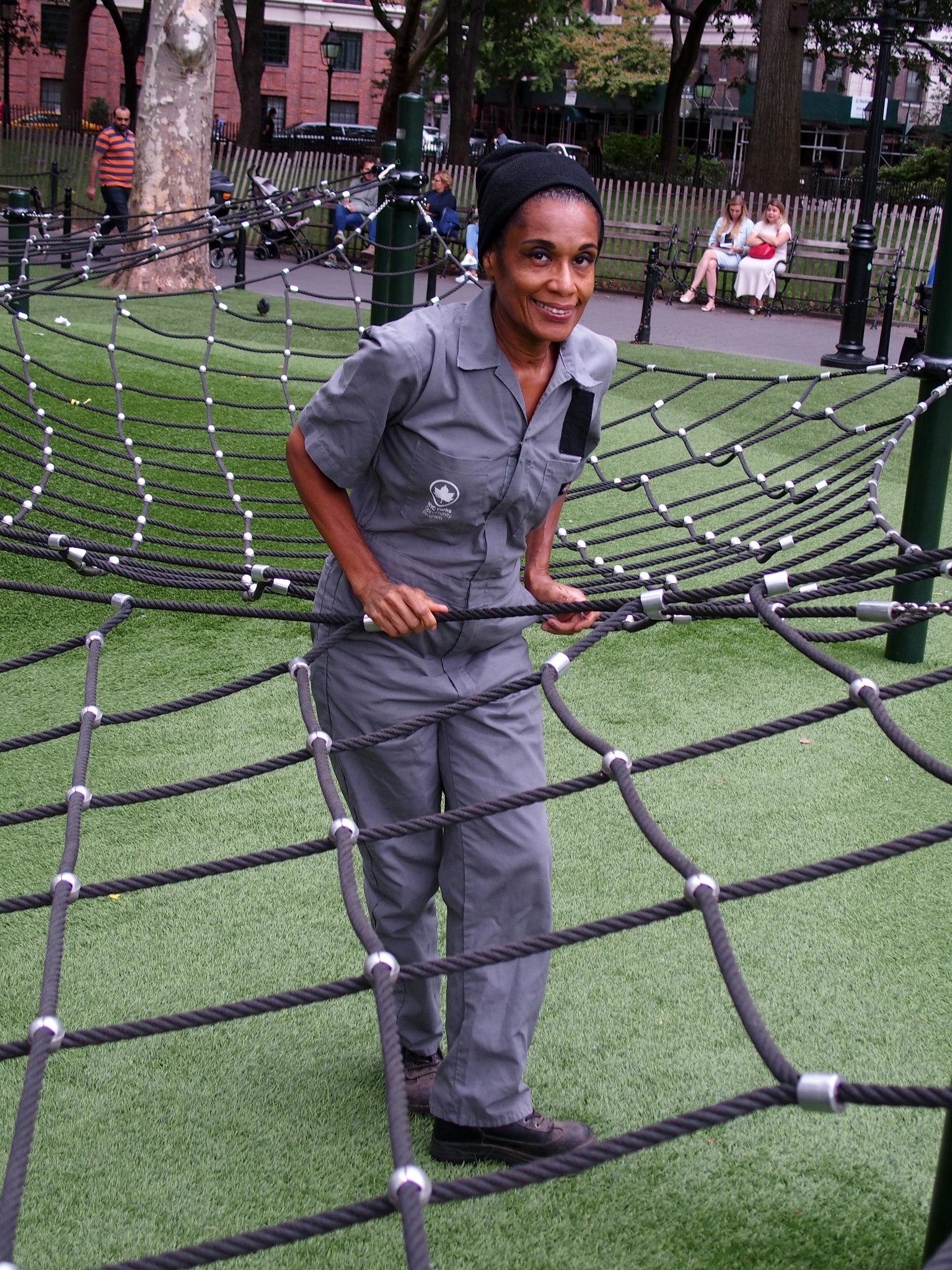 Youth Activities Coordinator, Miss Debbie stands in the middle of a climbing net in the small children's playground
