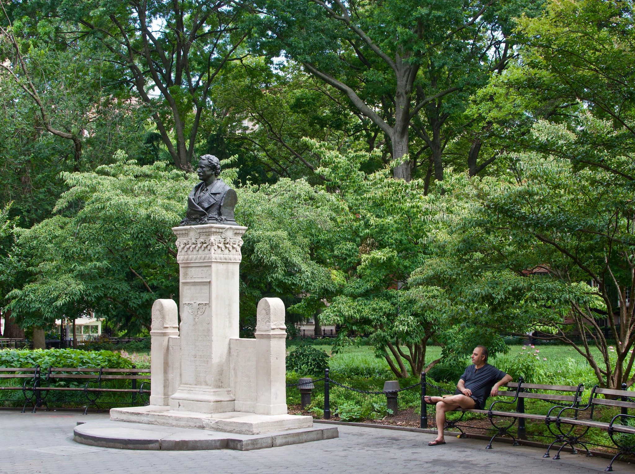a person sitting on a bench looking at Alexander Lyman Holley Monument
