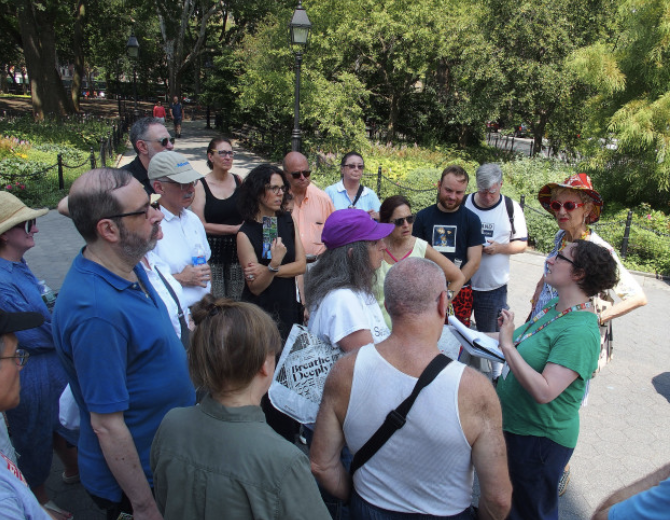 a group of people listening to a tour guide in the park
