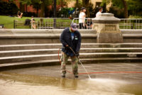 a park employee uses a power washer on the fountain