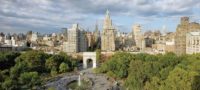 birds eye view of the park in the daytime including trees, fountain, arch, city skyline, and clouds