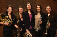 five women musicians pose with instruments and smile for camera