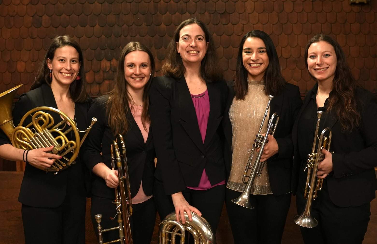 five women musicians pose with instruments and smile for camera