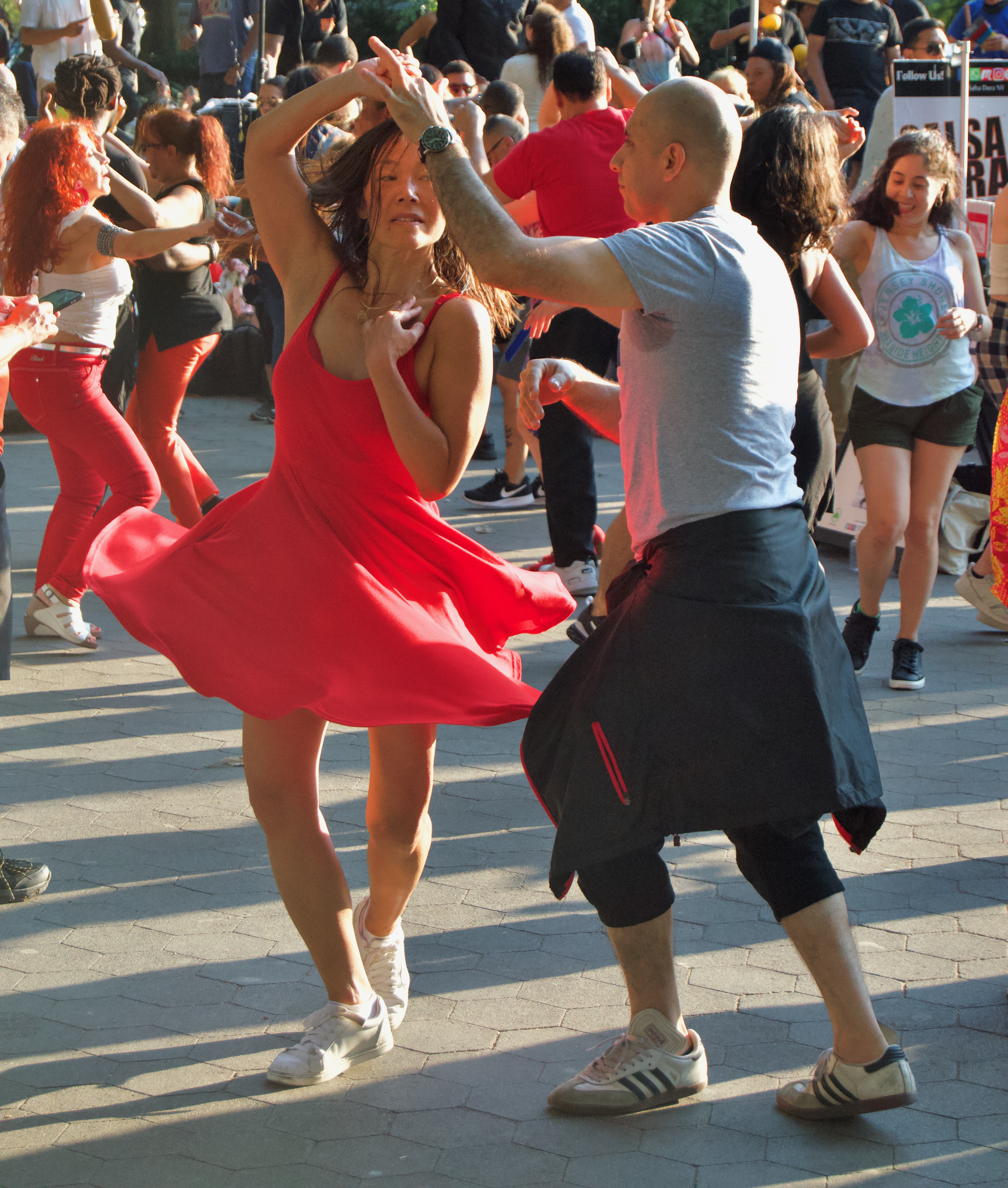 a lady in a red dress salsa dances with her partner