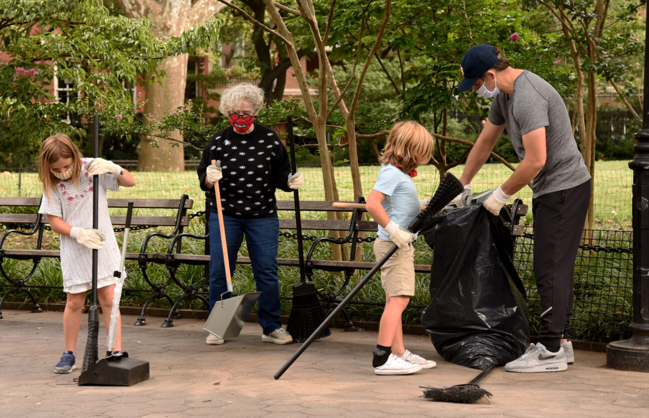 two adults and two children volunteer at a monthly park clean up