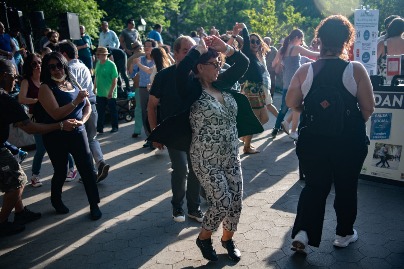 a woman twirls in a crowd of salsa dancing people